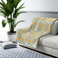 Load image into Gallery viewer, Floral patterned blanket draped over a sofa in a living room setting with a plant and rug.