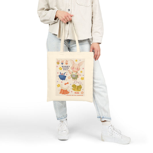 Person holding a tote bag with bunny cartoon characters on a white background