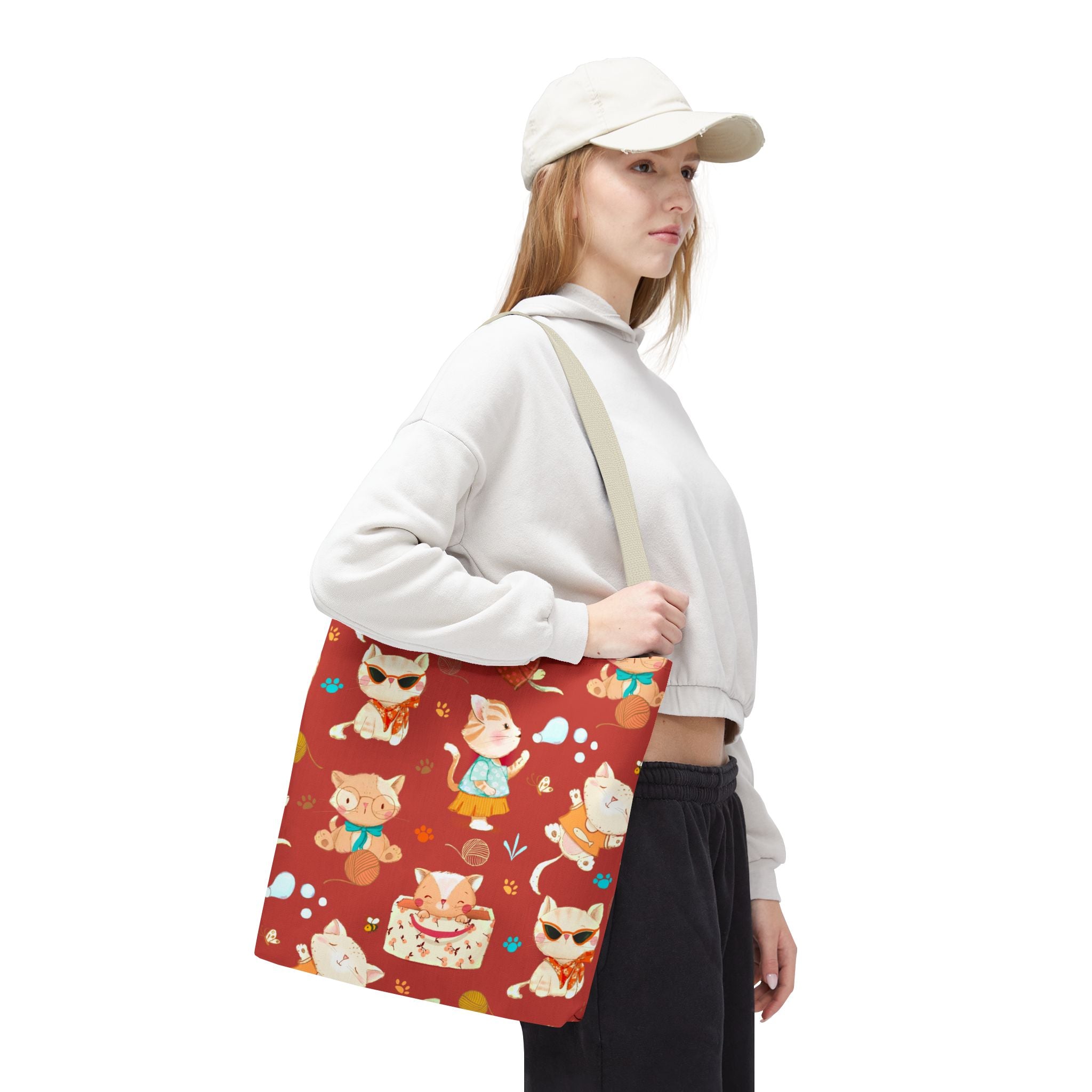 Person holding a red tote bag with cat pattern on a white background