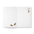 Load image into Gallery viewer, An open white notebook or journal laid flat on a white background, with small scattered autumn leaf illustrations in brown, tan, and muted green on the pages.
