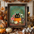 Load image into Gallery viewer, A framed autumn-themed painting of a black cat in an orange pumpkin, displayed on a table surrounded by pumpkins, candles, dried grass, and fall decorations.
