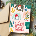 Load image into Gallery viewer, Christmas card with penguins and text 'Warm Wishes' surrounded by festive decorations and ugly sweaters

